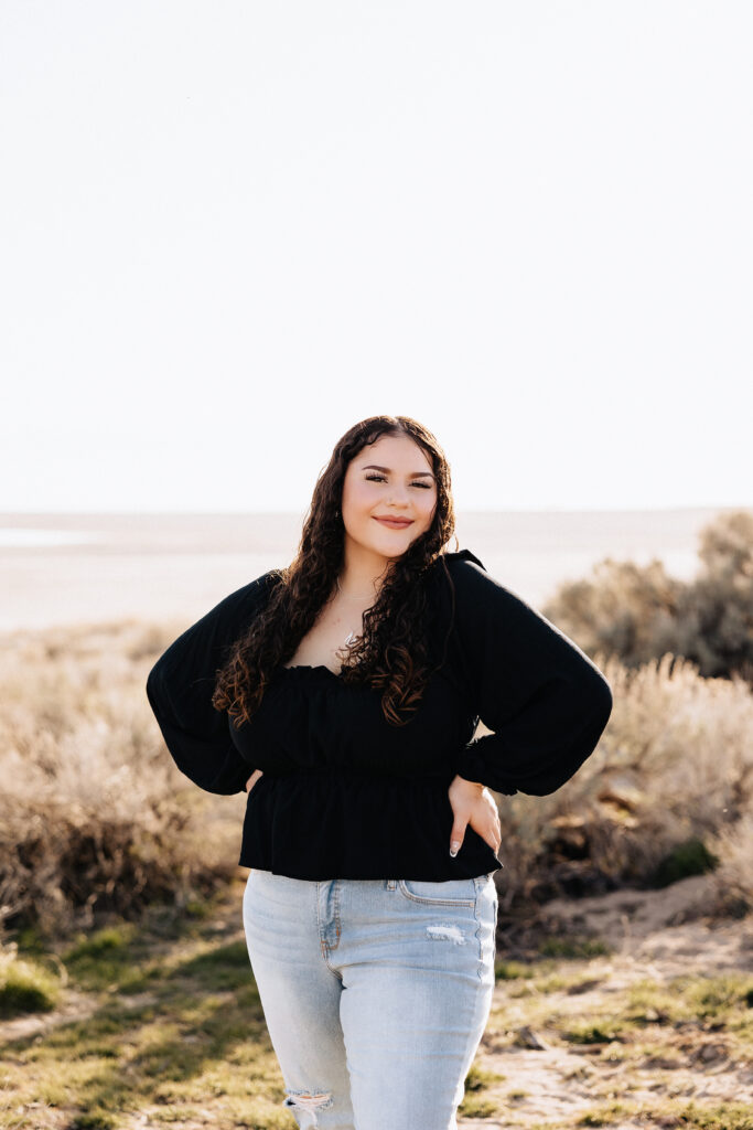 Maleah has both hands on hip posing for graduation pictures at Antelope Island State Park.