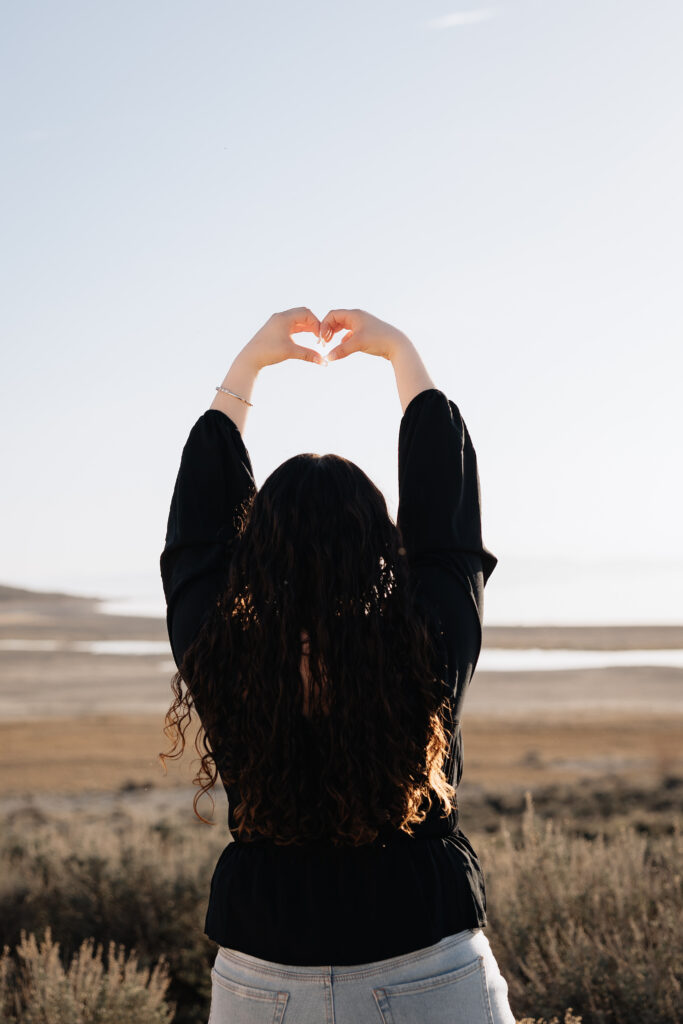 Maleah doing a heart shape with her hands facing away from the camera.