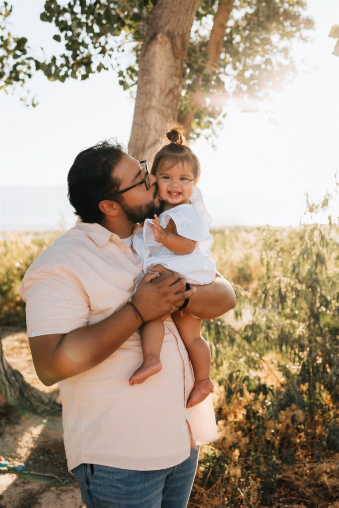 Daddy kissing baby on cheek.