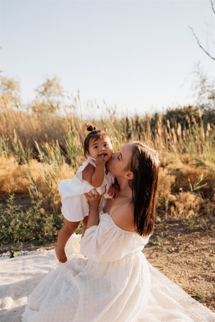 Mom giving baby a kiss on cheek.